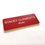 A red name badge with black engraved text. With rounded corners