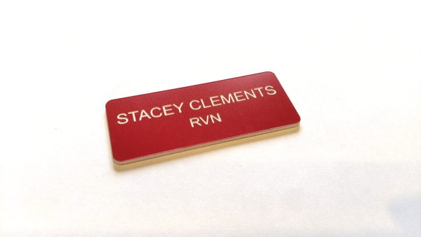 A red name badge with black engraved text. With rounded corners