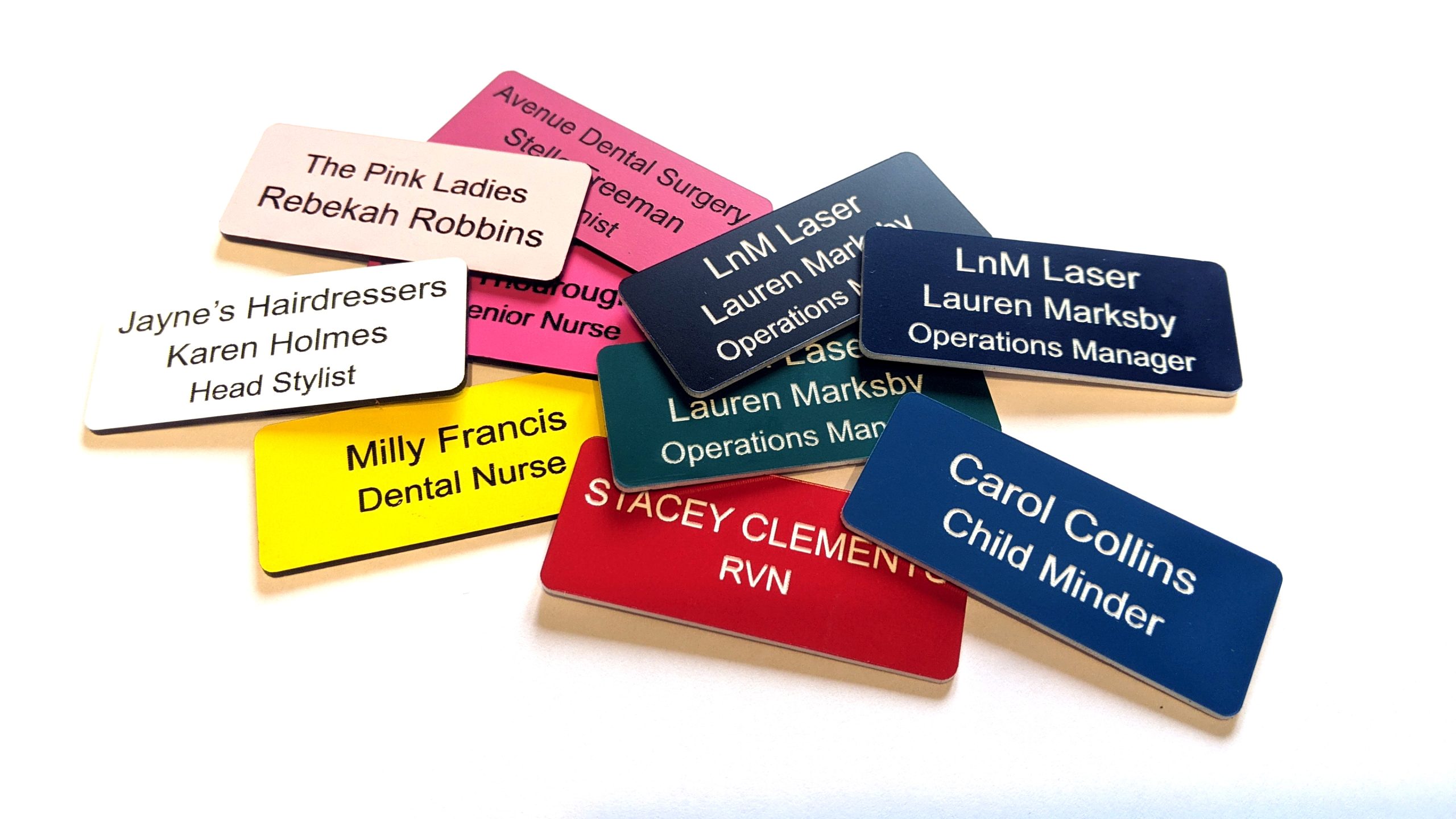 Various engraved name badges engraved with contrasting text on, With rounded corners.