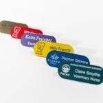 Various pill shaped engraved name badges with and without logos on the left.