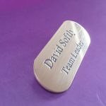 A distinctive, engraved brass badge resembling a pill, designed for durability and visual appeal
