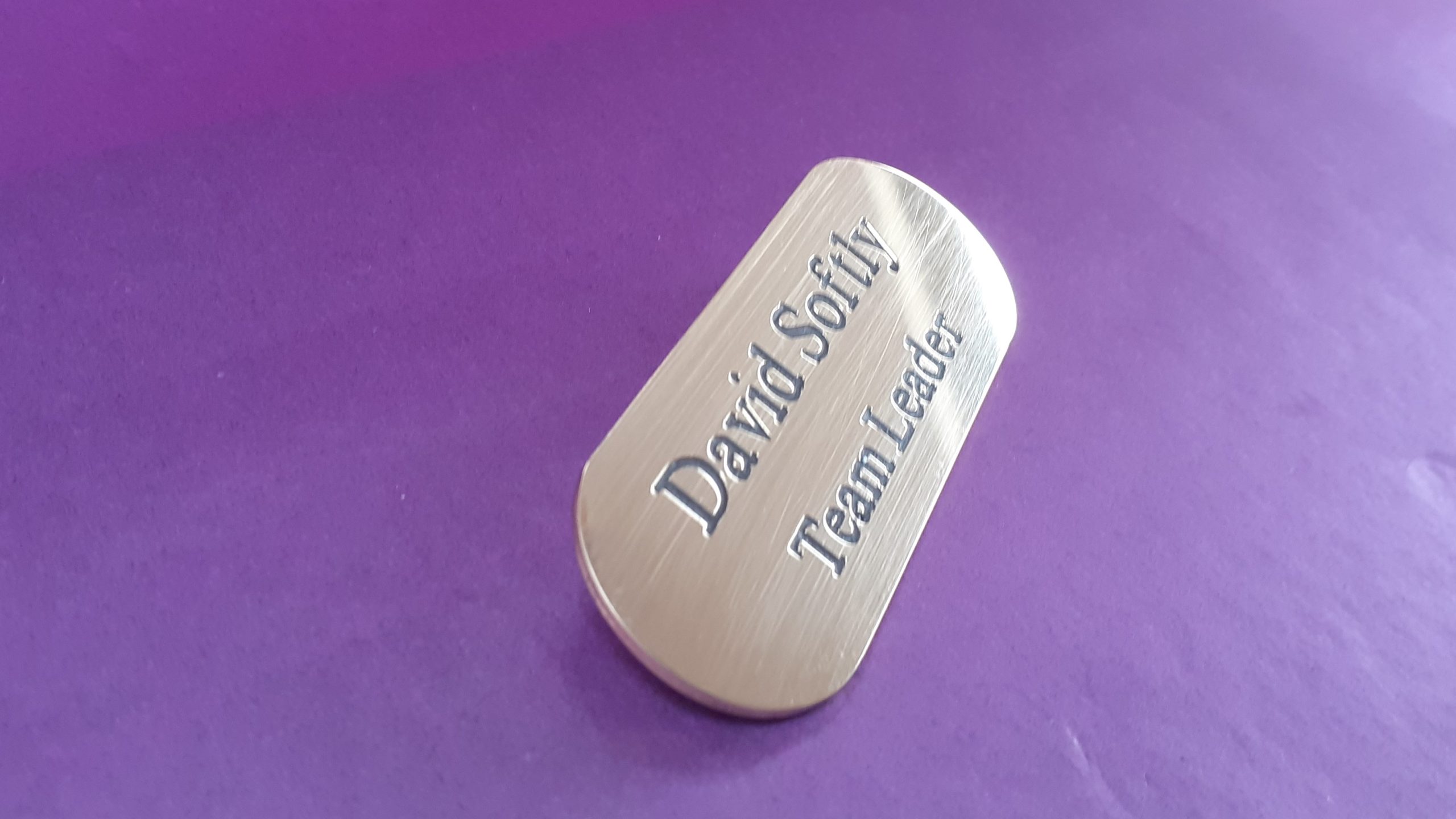 A distinctive, engraved brass badge resembling a pill, designed for durability and visual appeal
