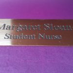 Polished rectangle brass name badge, featuring black engraved text
