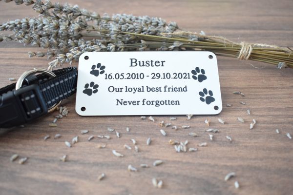 4" x 2 pet memorial plaque, Black rectangle plaque with white engraving text and rounded corners and four screw holes with two paw prints either side of the text