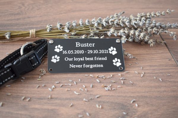 4" x 2 pet memorial plaque, Black rectangle plaque with white engraving text and rounded corners and four screw holes with two paw prints either side of the text