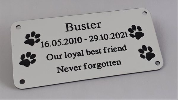 4" x 2 pet memorial plaque, white rectangle plaque with black engraving text and rounded corners and four screw holes with two paw prints either side of the text