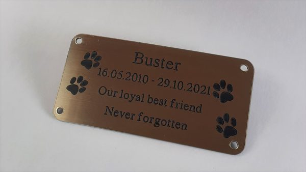 4" x 2 pet memorial plaque, gold rectangle plaque with black engraving text and rounded corners and four screw holes with two paw prints either side of the text