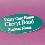 Engraved teal-green oval name badge, engraved with white text.