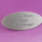 Engraved brushed silver oval name badge, engraved with black text.