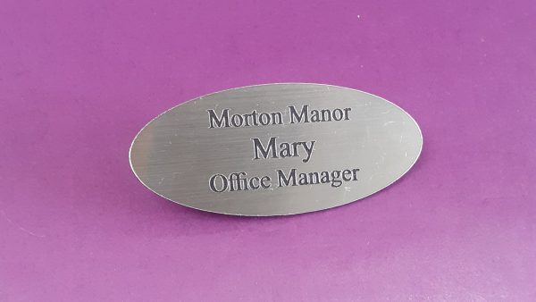 Engraved brushed silver oval name badge, engraved with black text.