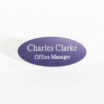 An oval-shaped purple name badge with white engraved text