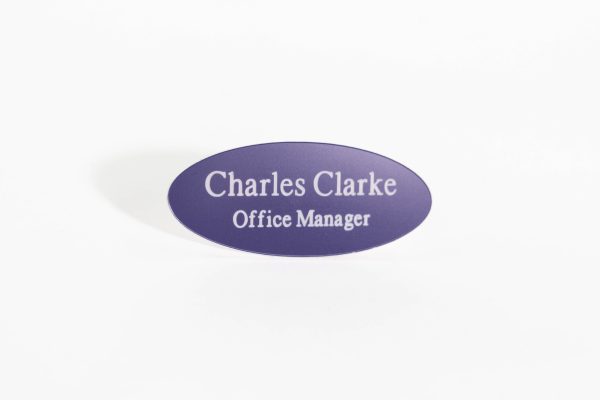 An oval-shaped purple name badge with white engraved text