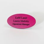 An oval-shaped dark pink name badge with black engraved text