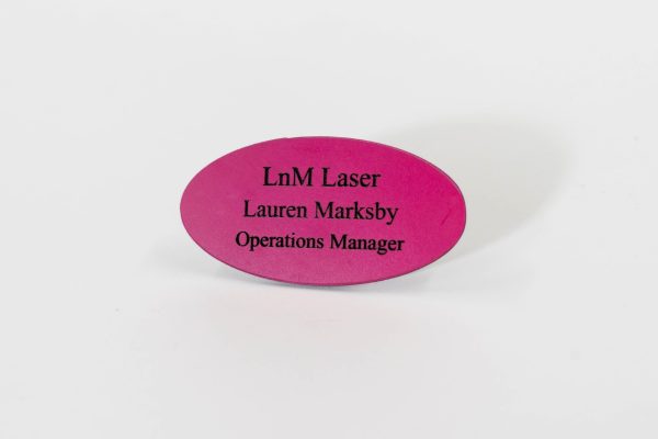 An oval-shaped dark pink name badge with black engraved text
