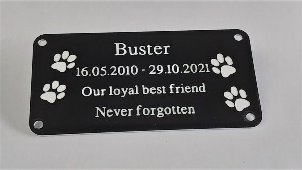 4" x 2 pet memorial plaque, Black rectangle plaque with white engraving text and rounded corners and four screw holes with two paw prints either side of the text
