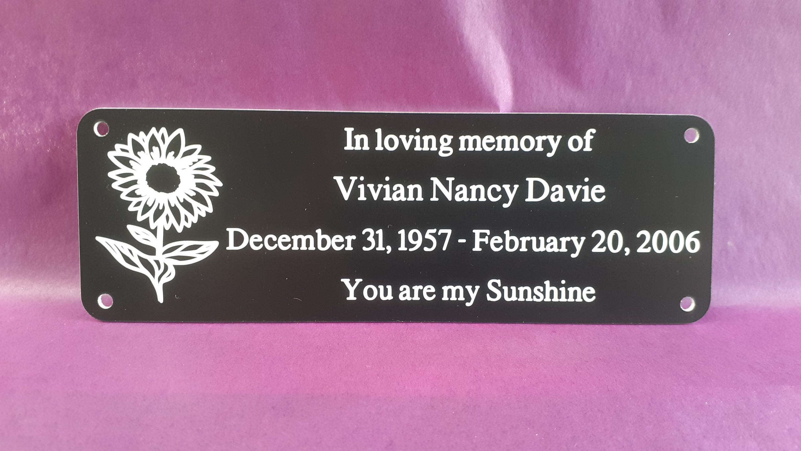 Personalised bench Plaques - 6" x 2" with decorative sunflower on the left-hand side of the white engraved text, 4 screw holes in each corner.