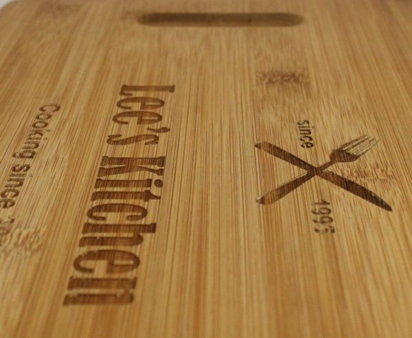 Close up of a bamboo chopping board with heartfelt engraving - 'Lee's kitchen - Cooking since 2019'