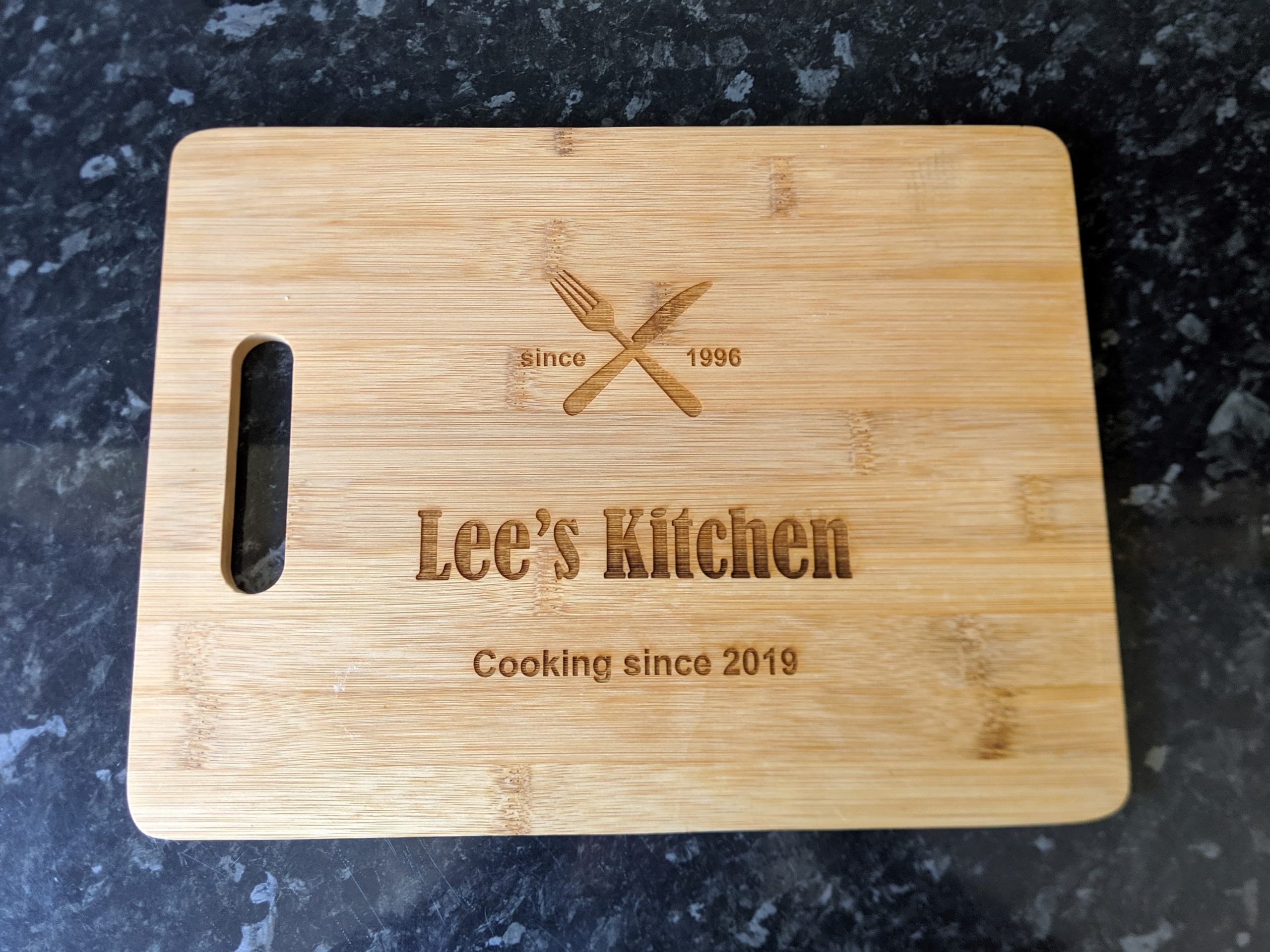 Close up of a bamboo chopping board with heartfelt engraving – ‘Lee’s kitchen – Cooking since 2019’
