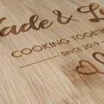 Close up of a bamboo chopping board showcasing 'Jade & Lee Cooking Together Since 2019' and two lovely love hearts.
