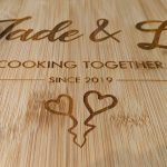 Close up of a heart-shaped bamboo chopping board with heartfelt engraving - 'Jade & Lee - 2019' and two sweet love hearts