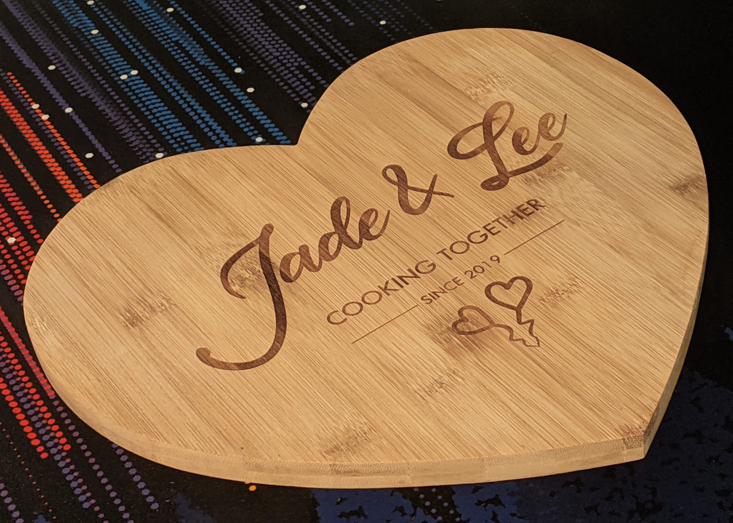 Personalised heart bamboo cutting board featuring Jade and Lee's culinary journey since 2019 with two charming love hearts.