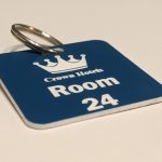 Blue keyring with white text showing a crown logo and a door number