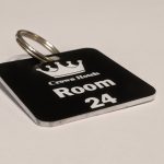Black keyring with white text showing a crown logo and a door number