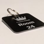 Black keyring with white text showing a crown logo and a door number