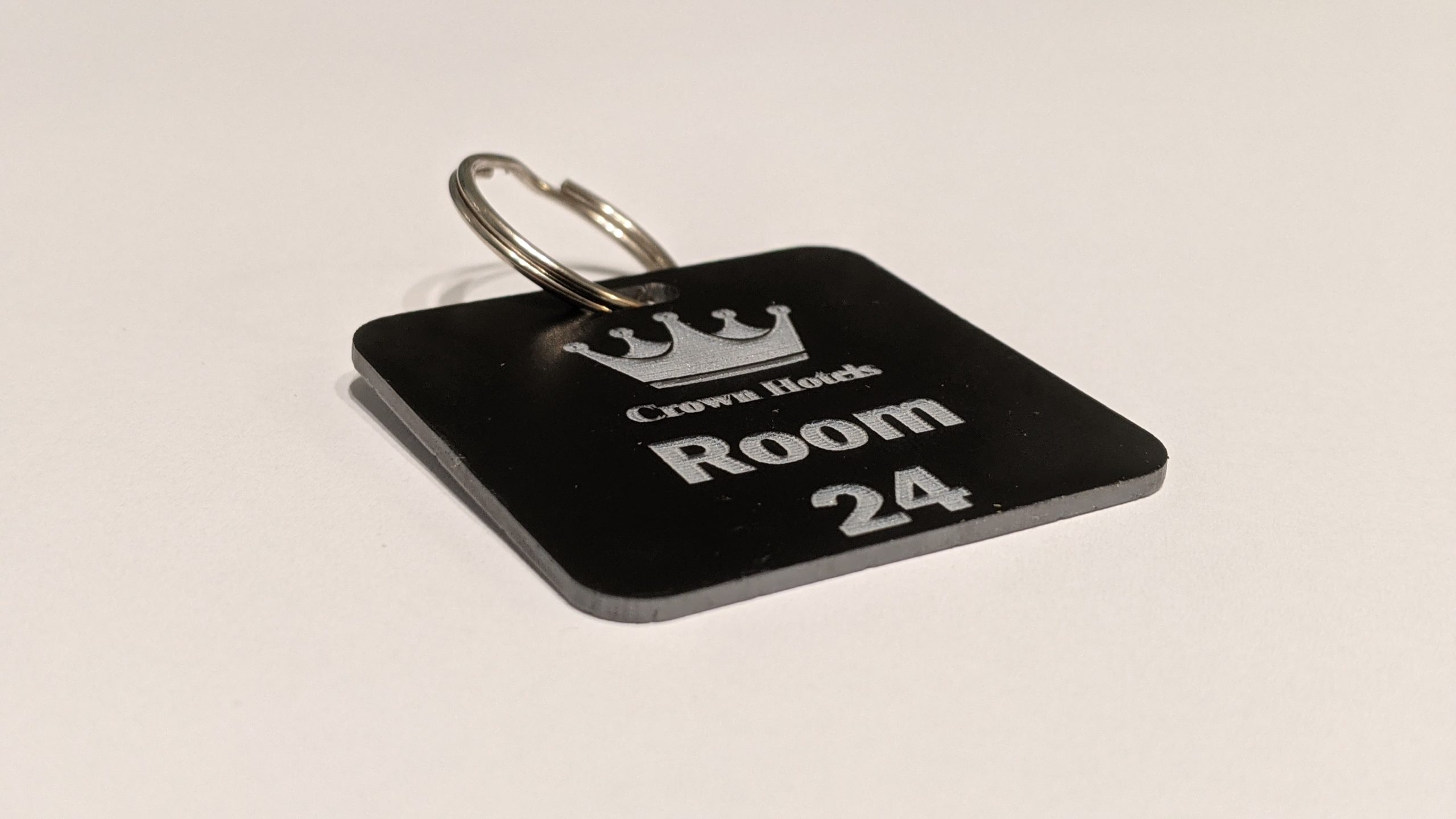 Black keyring with white text showing a crown logo and a door number