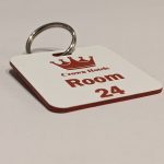 Red keyring with white text showing a crown logo and a door number