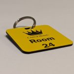 Yellow keyring with black text showing a crown logo and a door number
