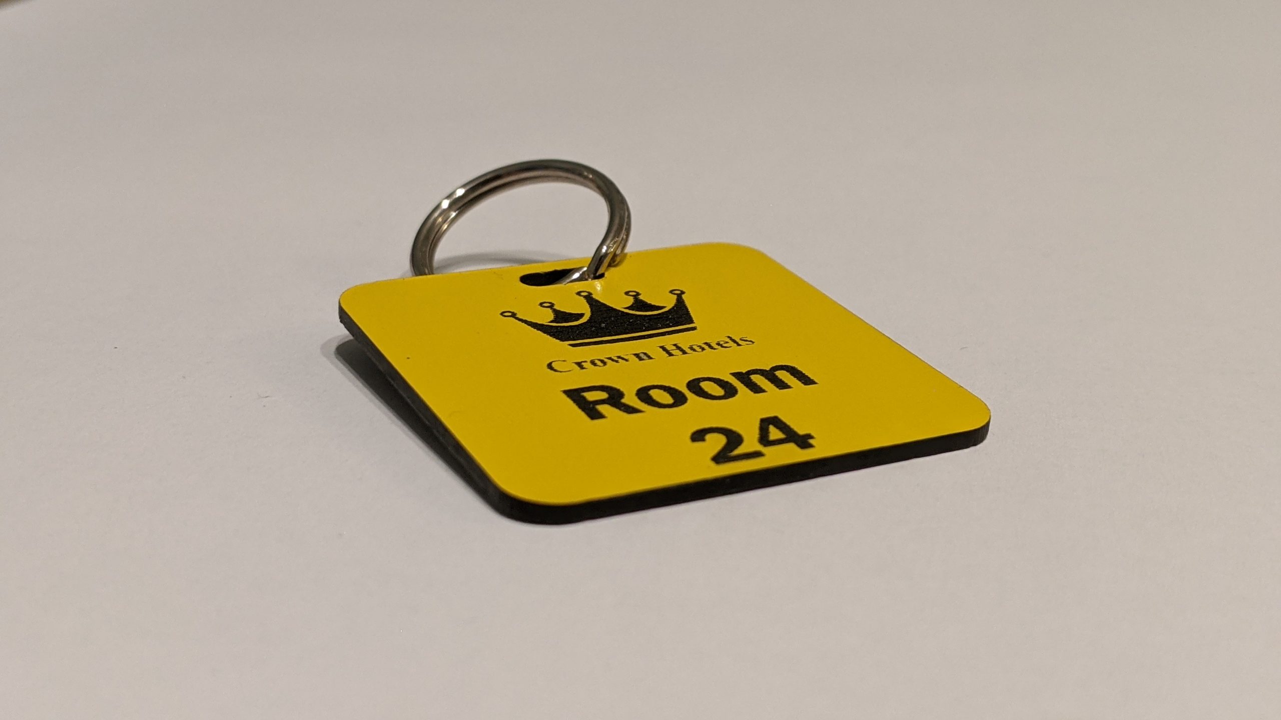 Yellow keyring with black text showing a crown logo and a door number
