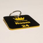 Black keyring with yellow text showing a crown logo and a door number