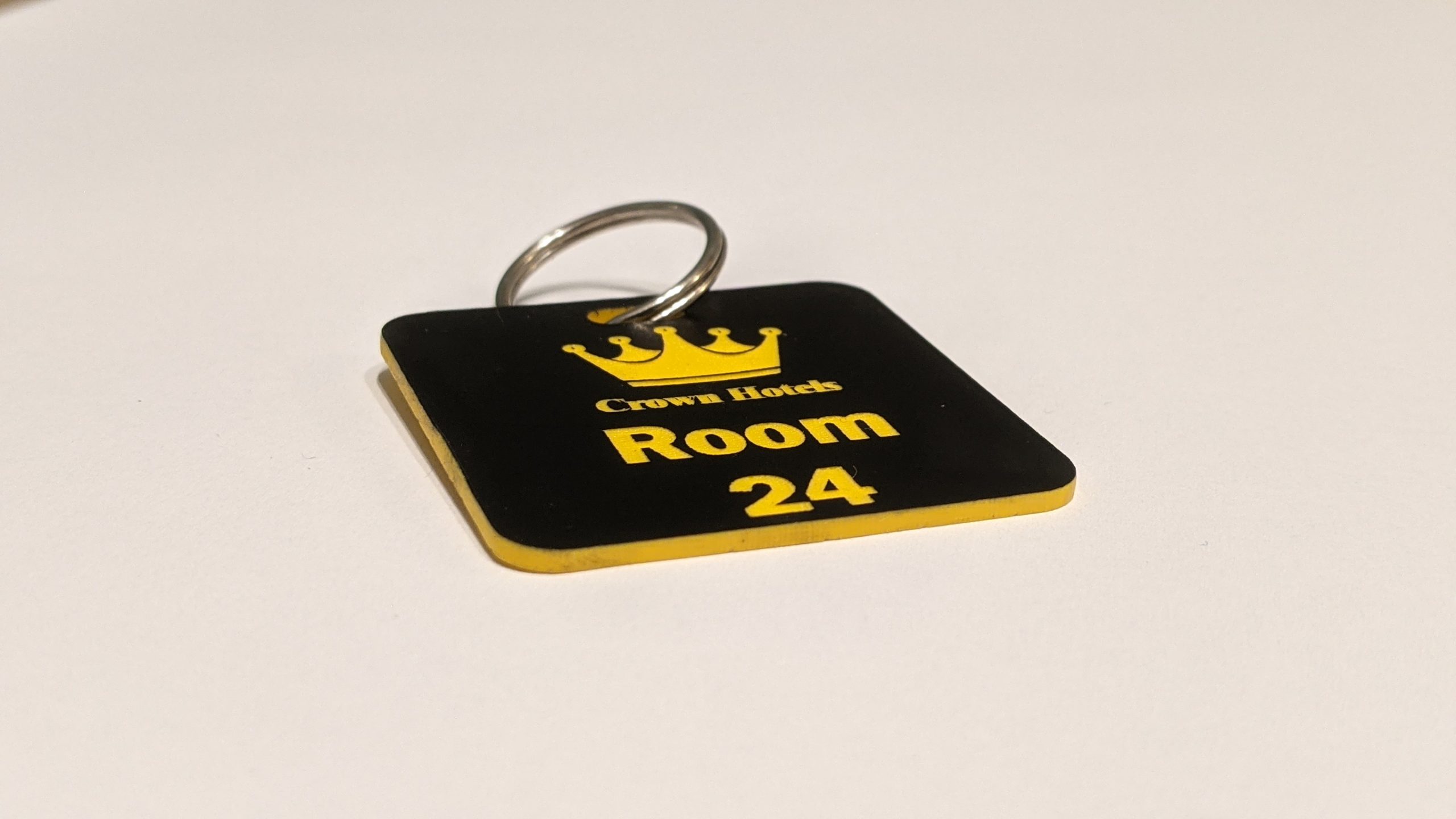 Black keyring with yellow text showing a crown logo and a door number