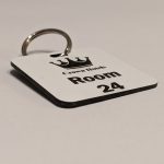 White keyring with black text showing a crown logo and a door number