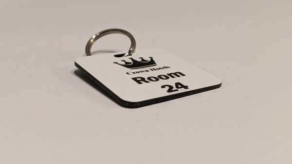 White keyring with black text showing a crown logo and a door number