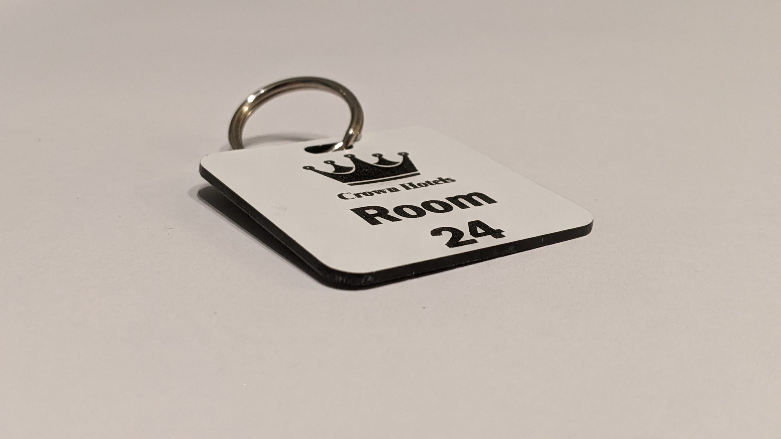 White keyring with black text showing a crown logo and a door number