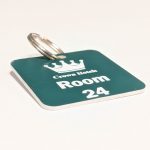 Teal green keyring with white text showing a crown logo and a door number