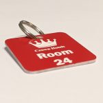 Red keyring with white text showing a crown logo and a door number