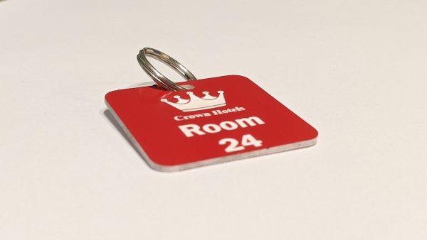 Red keyring with white text showing a crown logo and a door number