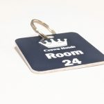 Navy Blue keyring with white text showing a crown logo and a door number
