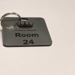 Brushed silver keyring with black text showing a crown logo and a door number