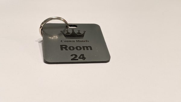 Brushed silver keyring with black text showing a crown logo and a door number