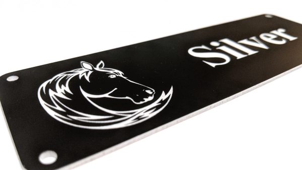 Close up of white engraving on black Stable Name Plaque - 6" x 2" with Left-Hand Horse's Head Design