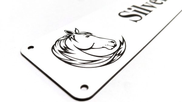 Close up of black engraving on white Stable Name Plaque - 6" x 2" with Left-Hand Horse's Head Design