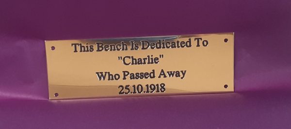 Elegant brass bench plaque, adorned with engraved text and black paint infill, secured by four sturdy screw holes.