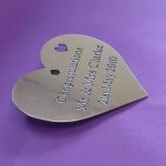 Brass heart plaque with deep engravings and black infill, featuring a delicate small heart in the upper right corner.