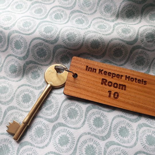 Cherry Wood Keyrings, Keyfobs 85mm x 30mm Compact wooden rectangle keyring with a key attached to the split ring featuring detailed engraving showing "Inn Keeper Hotels Room 10"