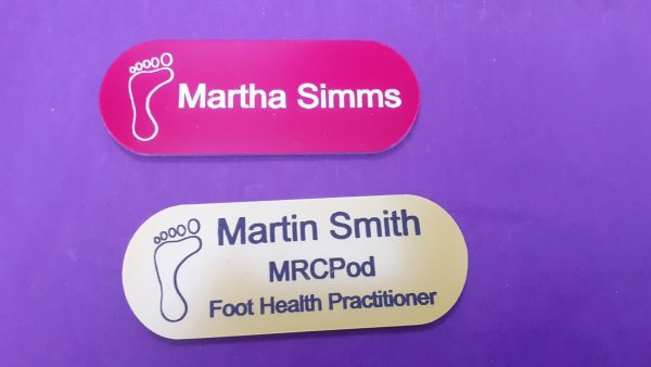 Red and Yellow name badge in the shape of a pill with foot logo and employee name and title engraved in black or white text