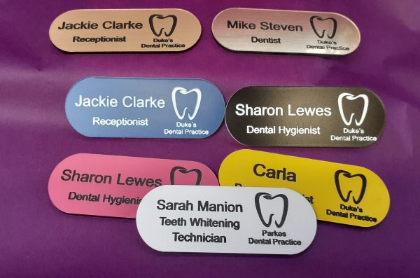 The tooth logo adds a dental or medical theme to the badges, making them suitable for dental professionals or health-related events. The pill-shaped design and colourful variations contribute to a visually appealing and customisable identification solution.